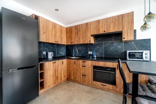 a kitchen with wooden cabinets and a stainless steel refrigerator at Apartament Słoneczny, PW Invest Home in Krapkowice