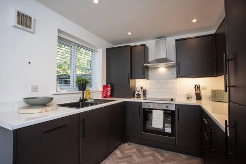 a kitchen with black cabinets and a sink at Arkless Grove Free Parking Wifi in Black Hill