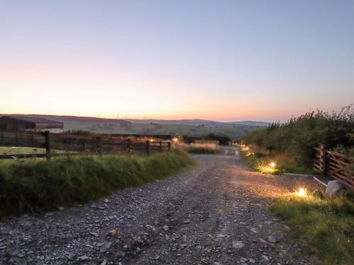 a dirt road with a sunset in the background at Weirglodd in Ruthin
