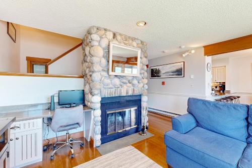 a living room with a blue couch and a fireplace at Lakefront At Winnipesaukee in Gilford