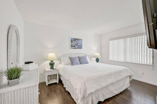 a white bedroom with a large bed and a window at Shore Serenity in Bradenton