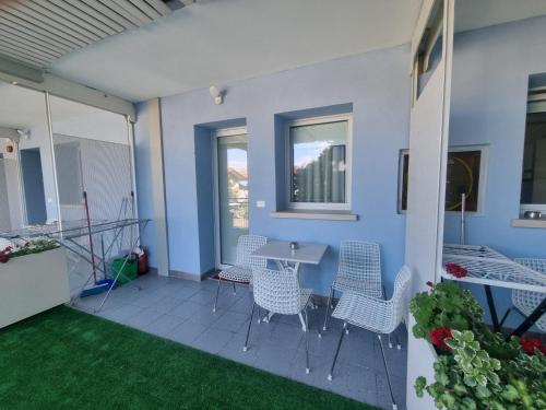 a patio with chairs and a table on a blue wall at Appart-Hotel Holiday in Lignano Sabbiadoro