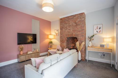 a living room with a white couch and a brick fireplace at Balmoral Gardens - Vacant Nests in North Shields