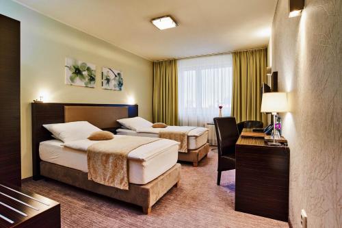 a hotel room with two beds and a desk at Privilege - EMPIRE Hotels Group in Košice