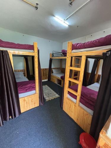 a room with three bunk beds in it at Beholden Stay and Cafe - A Luxury Boutique Hotel in Manali in Manāli