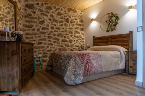 a bedroom with a bed and a stone wall at Casa Rural El Mesón 9 in Fermoselle