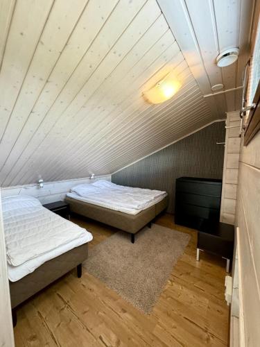 an attic room with two beds and a ceiling at Himos Kuikanhovi A in Jämsä
