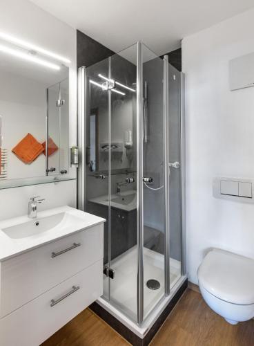 a bathroom with a glass shower and a sink at Bodensee Hotel Storchen in Uhldingen-Mühlhofen
