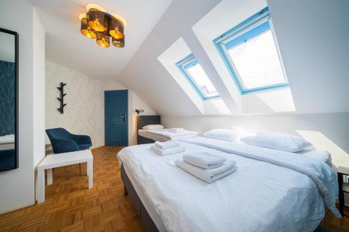 a attic bedroom with two beds and a chair at Naturální vinařství Tomáš Křížek, Penzion Dvorek in Dolní Dunajovice