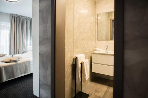 a bathroom with a sink and a bed and a mirror at Hotel Epic Centrum in Cisnădie