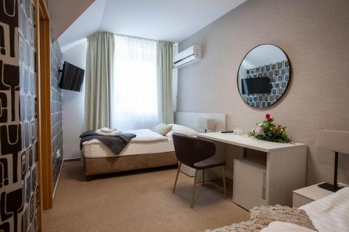 a hotel room with a bed and a desk and a mirror at Penzion Solid Spa in Mladá Boleslav