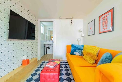 un salon avec un canapé orange et une télévision dans l'établissement Unique Vintage Vibes - Cozy Tiny Home close to UT, à Austin