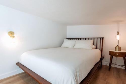 a bedroom with a white bed and a night stand at Cozy and Bright Mid-Century Gem in Eastside Action in Austin