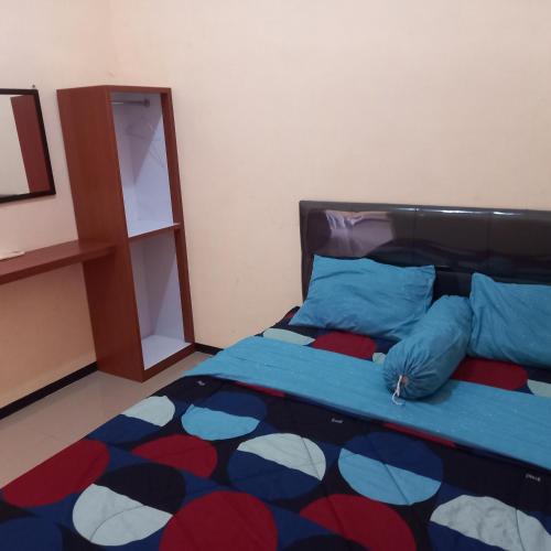 特勒贡Villa Labella BNS Batu的卧室里有一张床，上面有蓝色枕头和一面镜子