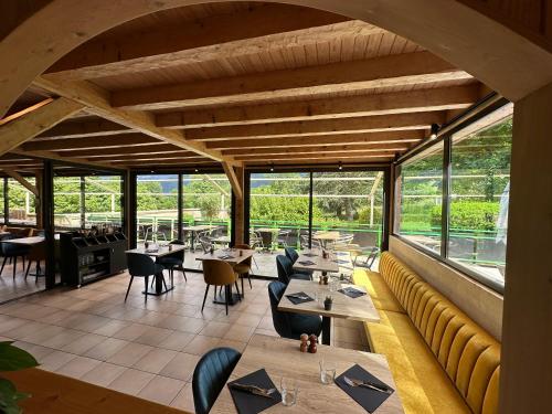 a restaurant with tables and chairs and windows at Logis Le Chalet in Saint-Maurice-en-Trièves