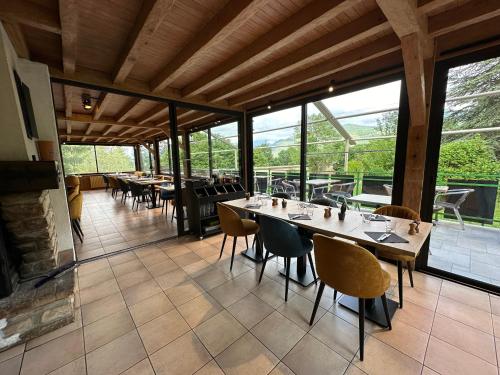 a dining room with tables and chairs and windows at Logis Le Chalet in Saint-Maurice-en-Trièves
