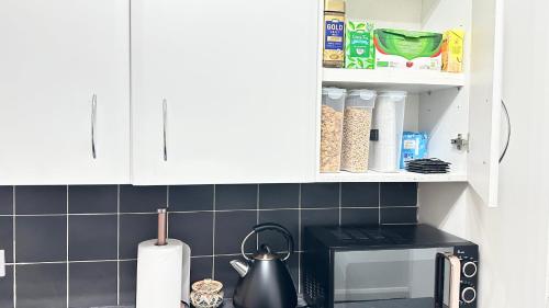 a kitchen with white cabinets and a tea kettle at 8-Sleeper 4BR 4Bed 2Bath Wi-Fi Garden Tv Beach in Portsmouth