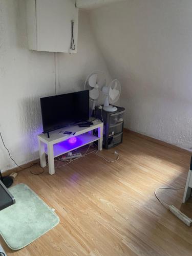 Cette chambre dispose d'une télévision et d'une table avec des lumières violettes. dans l'établissement Ritaj, à Paris