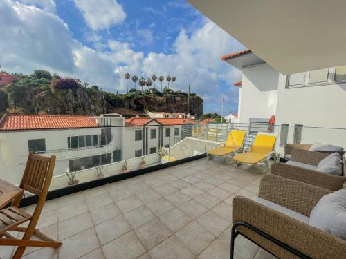 a balcony with chairs and a view of a building at Villa Supranee Relaxation in Câmara de Lobos