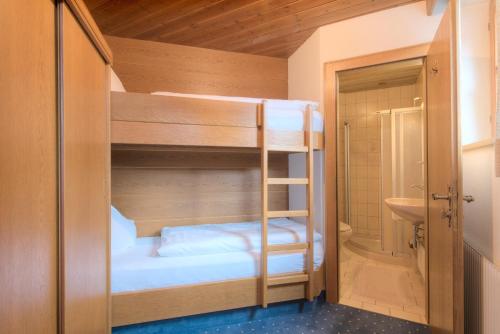 a bunk room with two bunk beds and a bathroom at Hotel Garni Almjur in Sankt Anton am Arlberg