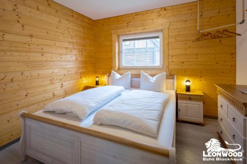 a bedroom with a white bed with wooden walls at Ferienwohnungen an der Hauptspree in Kolonie