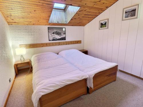 un lit dans une chambre avec un plafond en bois dans l'établissement Duplex 5/6 pers, aux pieds des pistes, proche commerces, balcon, WiFi, animaux OK - FR-1-182-137, à Méribel