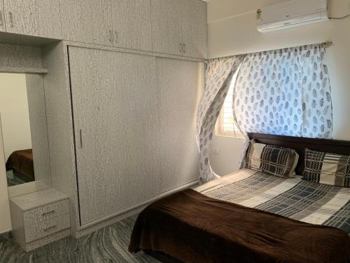 a small bedroom with a bed and a window at SAGAR NIWAS-1BHK and 2BHK short stay flats - NH HCL EC Bommasandra in Bengaluru