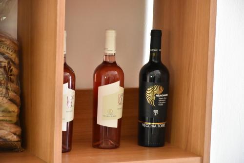 two bottles of wine in a wooden cabinet at Hotel Villa del Sole in Porto Cesareo