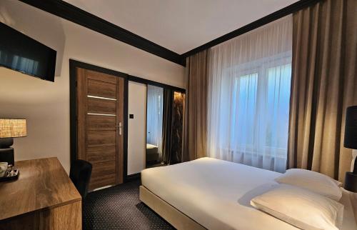 a hotel room with a bed and a desk and window at Willa Pirs in Warsaw