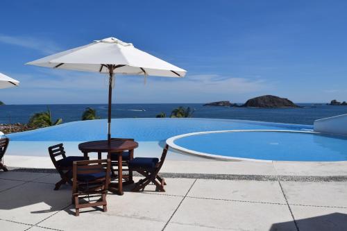 a table and chairs with an umbrella next to a pool at IXTAPA Zihuatanejo Alegria y Familia in Ixtapa