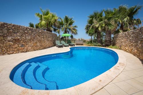 ナダにある4 Bedroom Farmhouse with Private Pool & Viewsのヤシの木と椅子2脚が備わる青いスイミングプール