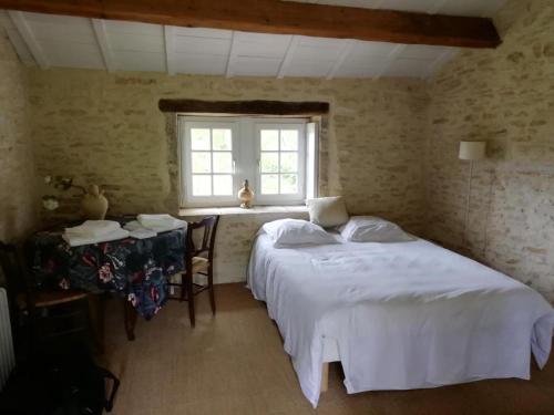 une chambre avec un lit, une table et une fenêtre dans l'établissement Une Maison de campagne en Bourgogne du Sud, à Tournus