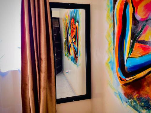a mirror on a wall with a colorful painting at Saginias Nest in Kyambogo
