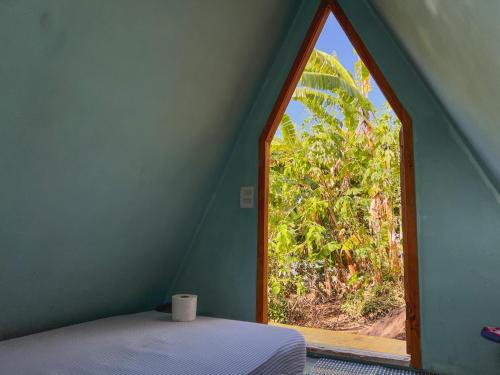 a window in a room with a bed and a tree at Camping Filhos da Floresta - Vale do Capão in Vale do Capao