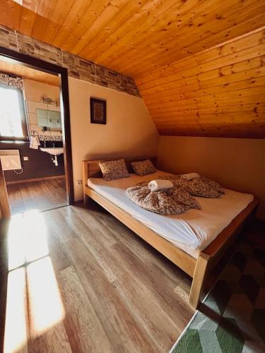 a bed in a room with a wooden ceiling at Csodaszarvas Vendégházak in Rábahidvég