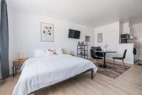 a white bedroom with a bed and a table and chairs at Cosy Place Brussels Expo 200 in Brussels