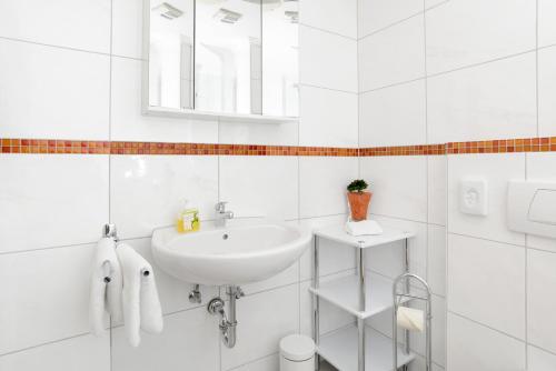 a white bathroom with a sink and a mirror at Berghüs Schratt - EINFACH ANDERS - Ihr vegetarisches und veganes Biohotel in Oberstaufen