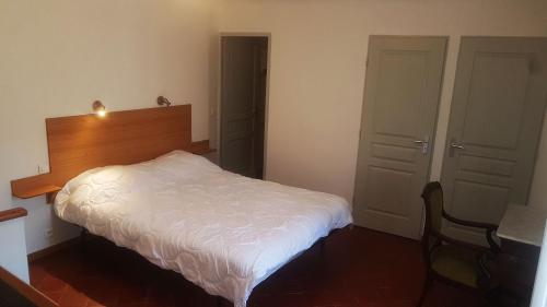 - une chambre avec un lit blanc et une tête de lit en bois dans l'établissement Le Vieux Moulin, au Tholonet