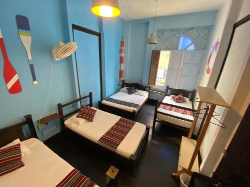 a room with three beds and a room with surfboards on the wall at Casona Don Juan Hostel in San Gil