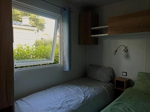 une petite chambre avec un lit et une fenêtre dans l'établissement Mobil home dans Camping 4 étoiles, à Pont-Aven