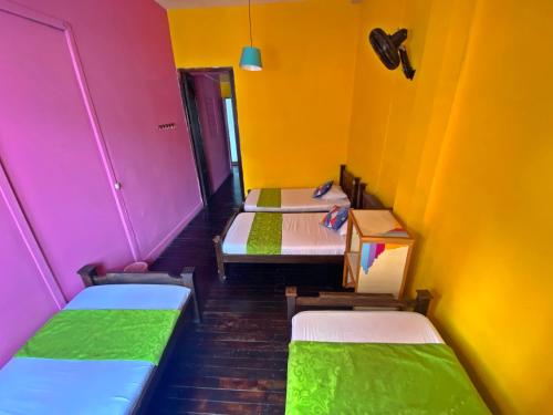 a room with three beds with colorful walls at Casona Don Juan Hostel in San Gil
