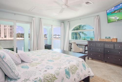 a bedroom with a bed and a desk and windows at Oceans Edge Retreat in Key Colony Beach