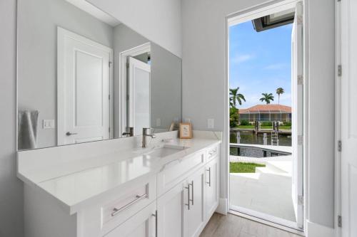 a white bathroom with a sink and a large mirror at Gulf Breezes in Marco Island