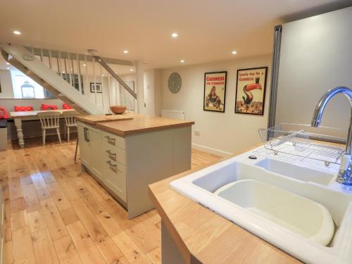 a large kitchen with a sink and a staircase at Stones Throw Cottage in Ambleside