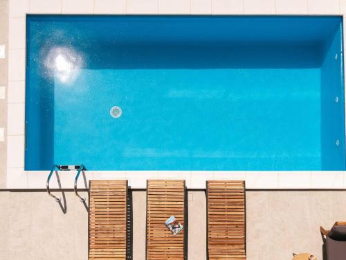 una piscina con una fila di sedie marroni accanto ad essa di Villa La Ze - Three Bedroom Villa with Swimming Pool a Rogoznica (Rogosnizza)