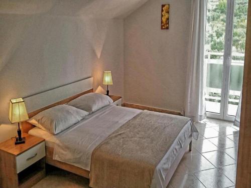 a bedroom with a bed with two lamps and a window at Apartments Bandalo - Standard Studio Apartment in Podstrana