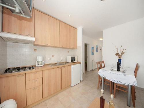 a kitchen with wooden cabinets and a table with a sink at Bertie's Lodge - Two Bedroom Apartment with Terrace and Sea View A1 in Smokvica