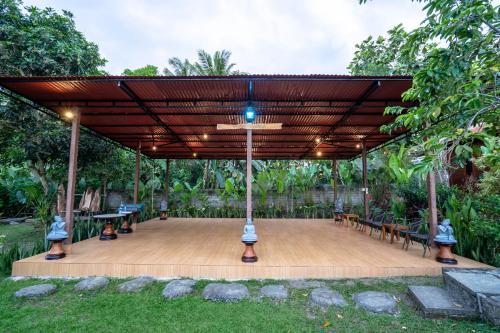 a pavilion with benches and tables in a park at The Dukuh Retreat in Tabanan