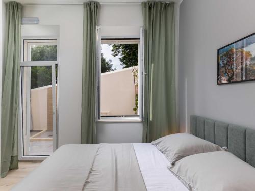 ein Schlafzimmer mit einem Bett und einem Fenster in der Unterkunft Apartments aMare - Three Bedroom Apartment with Terrace and Jacuzzi in Dubrovnik