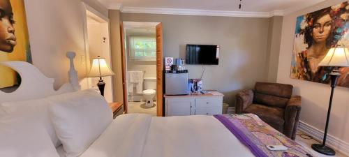 Caye Caulker Boutique Guesthouse 5 في كاي كولكر: غرفه فندقيه سرير ابيض وكرسي